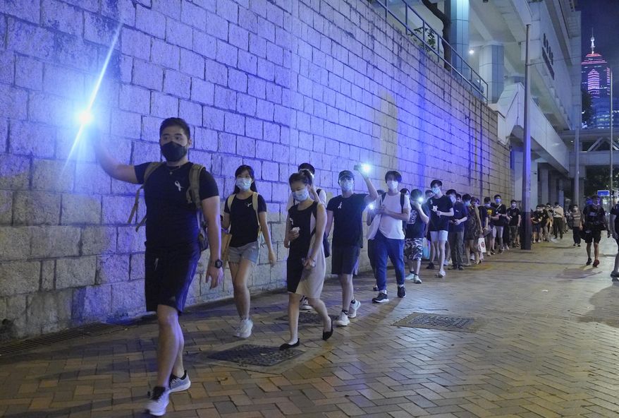 Protesters light their smartphone lights on the site to mark the one year anniversary where a man fell to his death after hanging a protest banner against the extradition bill on a building scaffolding in Hong Kong, Monday, June 15, 2020. Protesters in Hong Kong got the government to withdraw extradition legislation last year, but now they're getting a more dreaded national security law, and the message from Beijing is that protest is futile. (AP Photo/Vincent Yu)
