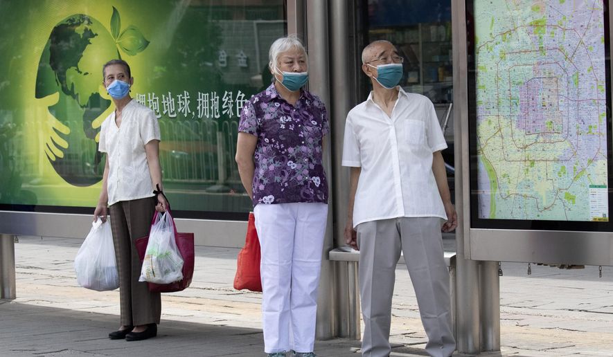 Elderly residents wearing masks to curb the spread of the coronavirus wait at a bus stop with a map of Beijing near a neighborhood under lockdown in Beijing Tuesday, June 16, 2020. Chinese authorities locked down a third neighborhood in Beijing on Tuesday as they rushed to prevent the spread of a new coronavirus outbreak that has infected more than 100 people in a country that appeared to have largely contained the virus. (AP Photo/Ng Han Guan)
