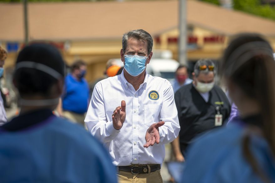 Georgia Governor Brian Kemp applauds healthcare workers for their service while touring a community COVID-19 testing site in the parking lot of La Flor de Jalisco #2 during a visit to Gainesville, Ga., Friday, May 15, 2020. (Alyssa Pointer/Atlanta Journal-Constitution via AP)