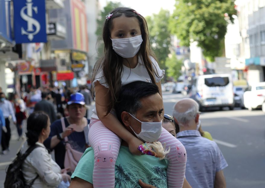 A man wearing a face mask to protect against the new coronavirus, holds a young girl on his shoulders, in Ankara, Turkey, Sunday, June 14, 2020. Turkey's President Recep Tayyip Erdogan has revealed Tuesday new plans to ease restrictions in place to curb the spread of the coronavirus, including the July 1 reopening of theaters, cinemas and other entertainment centers. (AP Photo/Burhan Ozbilici)