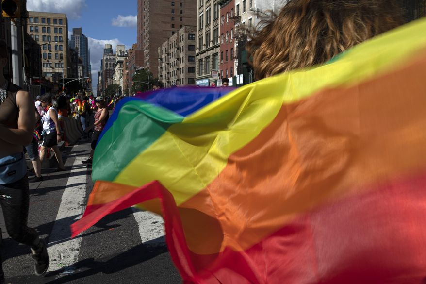 In this June 30, 2019, photo, paradegoers carrying rainbow flags walk down a street during the LBGTQ Pride march in New York, to celebrate five decades of LGBTQ pride, marking the 50th anniversary of the police raid that sparked the modern-day gay rights movement. (AP Photo/Wong Maye-E) ** FILE **