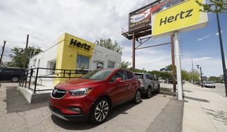 This May 23, 2020, photo shows rental vehicles parked outside a closed Hertz car rental office in south Denver. Hertz said Wednesday, June 17, it has put its plans to sell $500 million worth of stock on hold because the offering is being reviewed by the Securities and Exchange Commission. (AP Photo/David Zalubowski)
