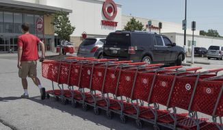 FILE - A Target employee returns shopping carts from the parking lot, in Omaha, Neb., Tuesday, June 16, 2020. Target Corp. says it’s permanently increasing starting hourly wages for its workers to $15 beginning July 5, several months ahead of schedule.   (AP Photo/Nati Harnik)