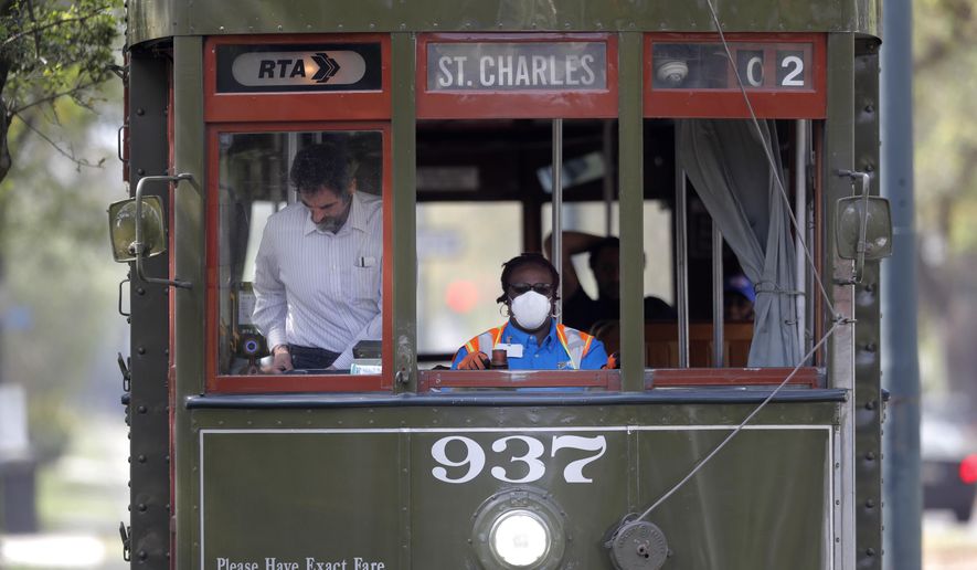 A streetcar conductor wears a mask as she runs her route on St. Charles Ave. in New Orleans, Thursday, March 19, 2020. Much of the city is shut down and many are taking precautions due to the coronavirus pandemic. (AP Photo/Gerald Herbert)
