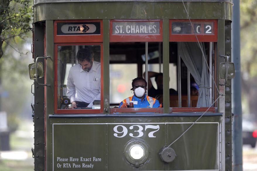 A streetcar conductor wears a mask as she runs her route on St. Charles Ave. in New Orleans, Thursday, March 19, 2020. Much of the city is shut down and many are taking precautions due to the coronavirus pandemic. (AP Photo/Gerald Herbert)