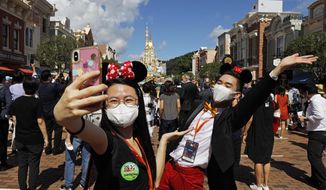 Visitors wearing face masks to prevent the spread of the new coronavirus, take a selfie at the Hong Kong Disneyland on Thursday, June 18, 2020. Hong Kong Disneyland on Thursday opened its doors to visitors for the first time in nearly five months, at a reduced capacity and with social distancing measures in place. The theme park closed temporarily at the end of January due to the coronavirus outbreak, and is the second Disney-themed park to re-open worldwide, after Shanghai Disneyland. (AP Photo/Kin Cheung)
