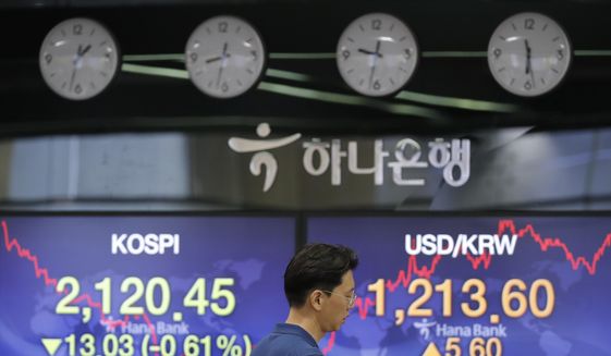 A currency trader walks by the screens showing the Korea Composite Stock Price Index (KOSPI), left, and the foreign exchange rate between U.S. dollar and South Korean won at the foreign exchange dealing room in Seoul, South Korea, Friday, June 19, 2020. Asian stock markets were mixed Friday after Wall Street closed little-changed amid as optimism about a possible global economic recovery was tempered by concern over rising coronavirus infections. (AP Photo/Lee Jin-man)