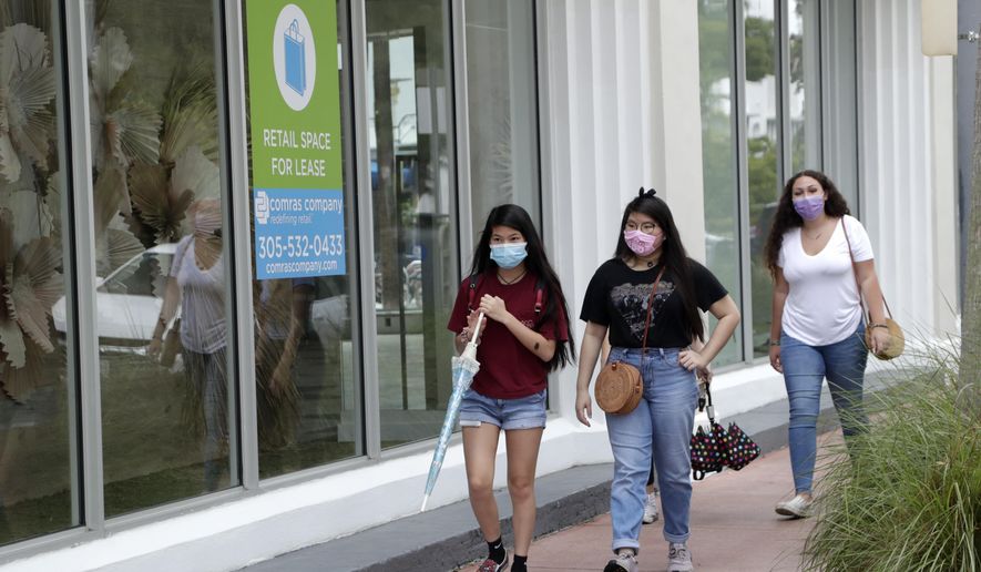 Shoppers wear protective face coverings as they walk past a vacant retail store for lease at Lincoln Road Mall during the new coronavirus pandemic, Wednesday, June 17, 2020, in Miami Beach, Fla. (AP Photo/Lynne Sladky)