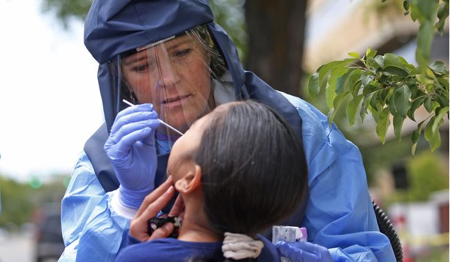 FILE - In this May 14, 2020, file photo, Salt Lake County Health Department public health nurse Lee Cherie Booth performs a COVID-19 test outside the department in Salt Lake City. State leaders said Wednesday, June 17, 2020, that updated plans intended to help drive economic recovery won't compromise the health of residents even though the state is experiencing a multi-week rise in cases. (AP Photo/Rick Bowmer, File)