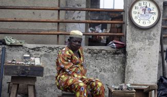 A watch repairer, wearing a face mask to protect himself from coronavirus, waits for customers on the street in Lagos Nigeria, Monday May 4, 2020. Though Nigeria begun a phased easing of its strict lockdown measures on Monday, its confirmed cases of coronavirus continue to increase. (AP Photo/Sunday Alamba)