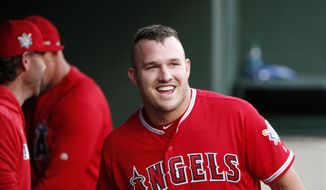 FILE - In this April 15, 2019, file photo, Los Angeles Angels designated hitter Mike Trout smiles in the dugout after he scored on a home run by Brian Goodwin against the Texas Rangers during the first inning of a baseball game in Arlington, Texas. If Major League Baseball and the players&#39; union can partially save its 2020 season, the potential 60-to 70-game season would be much shorter than the usual 162-game grind. It would look much more like a college baseball season. “If there&#39;s 60 games on the schedule, someone like Mike Trout is going to play 60 games,” former major league baseball player and college coach Tracy Woodson said. (AP Photo/Michael Ainsworth, File)