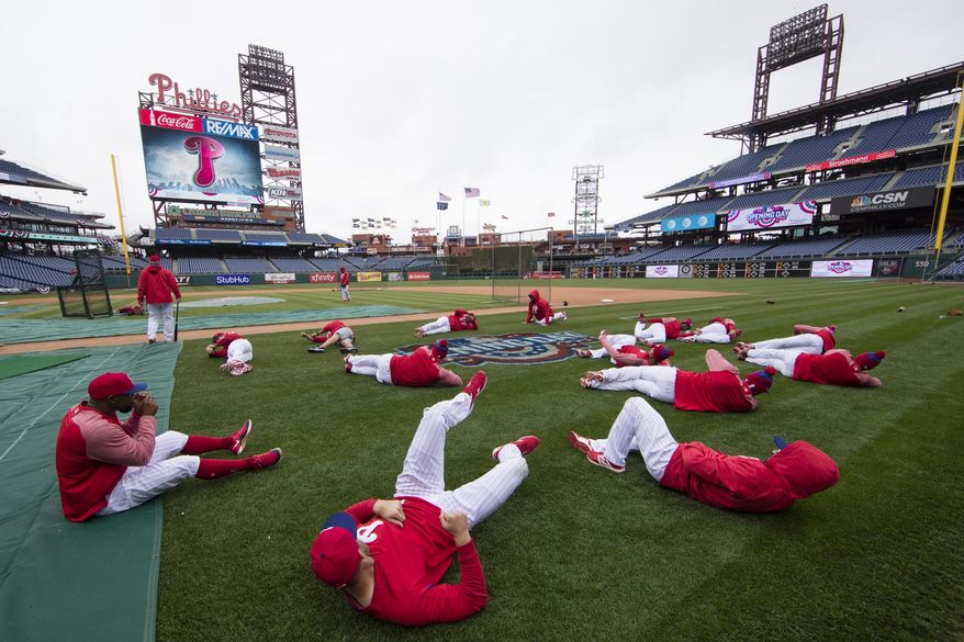 FILE - In this April 7, 2017, file photo, members of the Philadelphia Phillies stretch before the team's baseball game against the Washington Nationals in Philadelphia. Five players for the Philadelphia Phillies have tested positive for COVID-19 at the team's spring camp in Florida, prompting the club to indefinitely close the complex.The team also said Friday, June 19, 2020, that three staff members at the camp have tested positive. The club didn't identify any of those affected. (AP Photo/Matt Rourke, File)