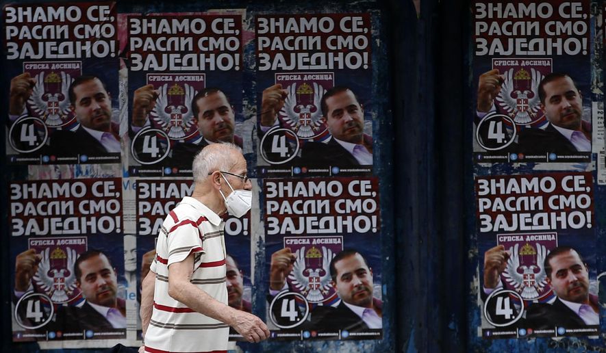 In this photo taken on Tuesday, June 16, 2020, a man wearing a face mask to protect against coronavirus, passes by election posters showing Serbian Right leader Misa Vacic, that reads: &amp;quot;We know each other well, we grew up together!&amp;quot;, in Belgrade, Serbia. Serbia is holding a parliamentary vote this weekend that takes place amid concerns over the continuing spread of the new coronavirus and political divisions in the Balkan country. (AP Photo/Darko Vojinovic)