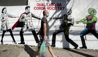 A man, wearing a protective face mask as a measure to curb the spread of the new coronavirus, walks past a mural depicting a tug-of-war between health workers and Brazil&#39;s President Jair Bolsonaro aided by a cartoon-styled coronavirus character, with a message that reads in Portuguese: &amp;quot;Which side are you on?,&amp;quot;  in Sao Paulo, Brazil, Friday, June 19, 2020. (AP Photo/Andre Penner)