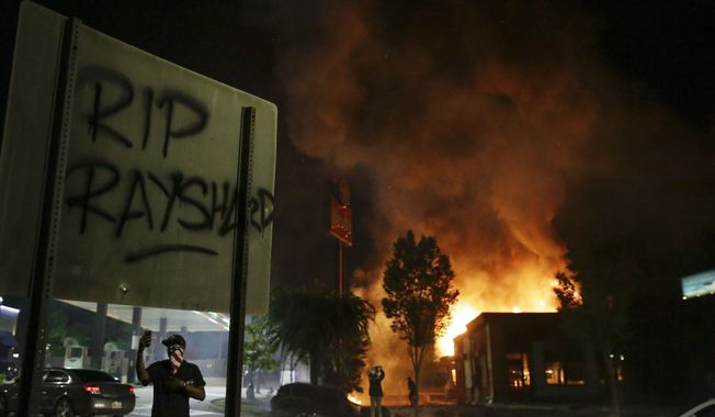 In this Saturday, June 13, 2020, file photo, &amp;quot;RIP Rayshard&amp;quot; is spray-painted on a sign as flames engulf a Wendy&#x27;s restaurant during protests in Atlanta. The restaurant was where Rayshard Brooks was shot and killed by police the previous evening following a struggle in the restaurant&#x27;s drive-thru line. (AP Photo/Brynn Anderson, File)