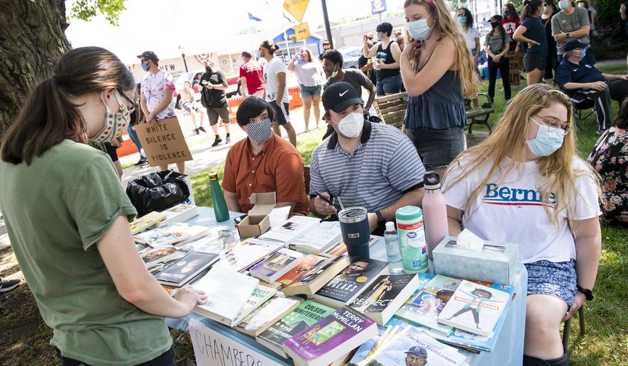 In this Tuesday, June 9, 2020 photo, In this Tuesday, June 9, 2020 phot0, dozens of books are available at a table run by the Chambersburg Book Drive during a Justice for George Floyd protest at the King Street Gazebo in Shippensburg, Pa. (Dan Rainville/The Evening Sun via AP)