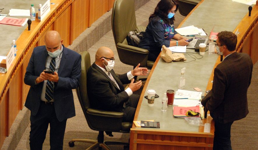 Democratic New Mexico state Rep. Javier Martinez, center, of Albuquerque, and Republican Rep. Gregg Schmedes, right, of Tijeras, converse Saturday, June 20, 2020, on the floor of the New Mexico House of Representatives in Santa Fe. The New Mexico Legislature met in a special session to address a gaping budget hole linked to the coronavirus and related economic upheaval. (AP Photo/Morgan Lee)