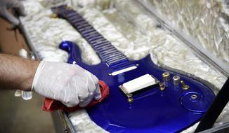 FILE - In this May 6, 2020 file photo, the “Blue Angel” Cloud 2 electric guitar custom-made for the musician Prince in the 1980s is polished at Julien&#39;s Auctions warehouse in Culver City, Calif. On Friday, June 19, 2020, the instrument shot past the top estimate of $200,000 it was expected to fetch at the Music Icons sale at the auction house. (AP Photo/Chris Pizzello)