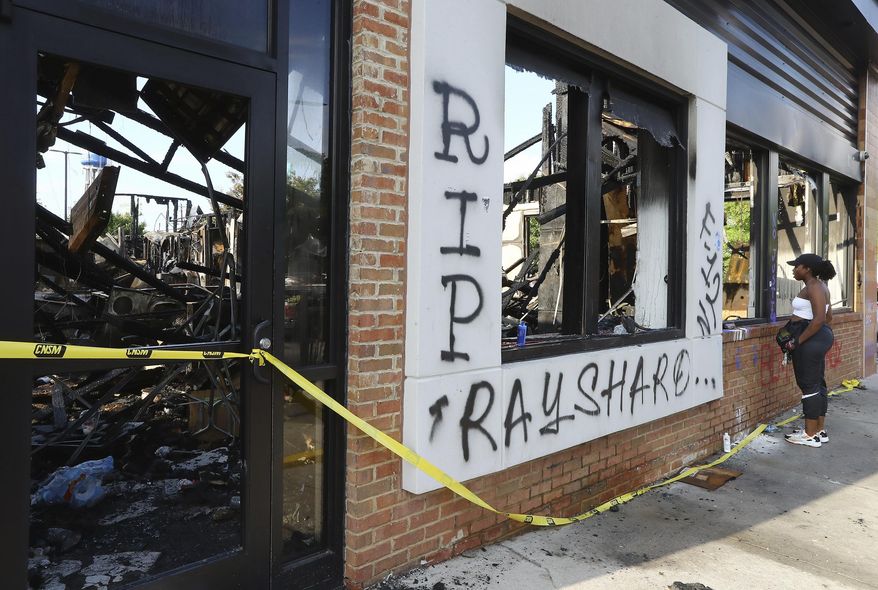 FILE - In this June 15, 2020 file photo, a woman looks at the interior of the burned Wendy's restaurant in Atlanta. Investigators said Saturday, June 20, they have issued an arrest warrant for a woman in the burning of a Wendy’s restaurant in Atlanta during protests over the police shooting of Rayshard Brooks. (Curtis Compton/Atlanta Journal-Constitution via AP)