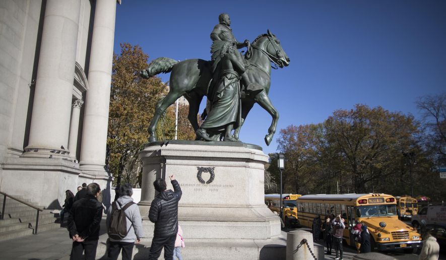 In this Nov. 17, 2017, file photo, visitors to the American Museum of Natural History in New York look at a statue of Theodore Roosevelt, flanked by a Native American man and African American man. The statue will be coming down after the museum&#39;s proposal to remove it was approved by the city. (AP Photo/Mary Altaffer, File)