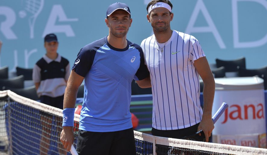 In this photo taken Saturday, June 20, 2020, Bulgaria's Grigor Dimitrov, right, poses for cameras with Croatia's Borna Coric during their semifinal match at a tournament in Zadar, Croatia. Dimitrov says he has tested positive for COVID-19 and his announcement led to the cancellation of an exhibition event in Croatia where Novak Djokovic was scheduled to play on Sunday. (AP Photo/Zvonko Kucelin)