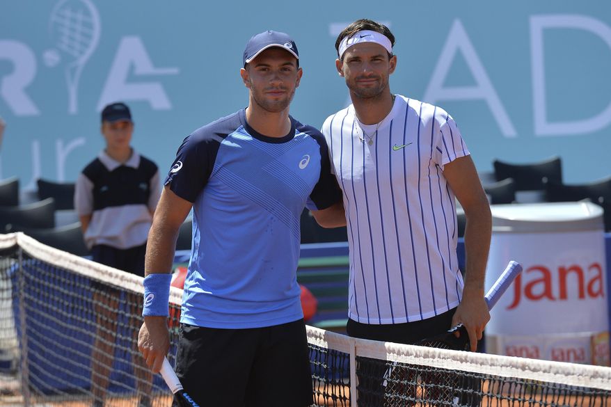 In this photo taken Saturday, June 20, 2020, Bulgaria's Grigor Dimitrov, right, poses for cameras with Croatia's Borna Coric during their semifinal match at a tournament in Zadar, Croatia. Dimitrov says he has tested positive for COVID-19 and his announcement led to the cancellation of an exhibition event in Croatia where Novak Djokovic was scheduled to play on Sunday. (AP Photo/Zvonko Kucelin)