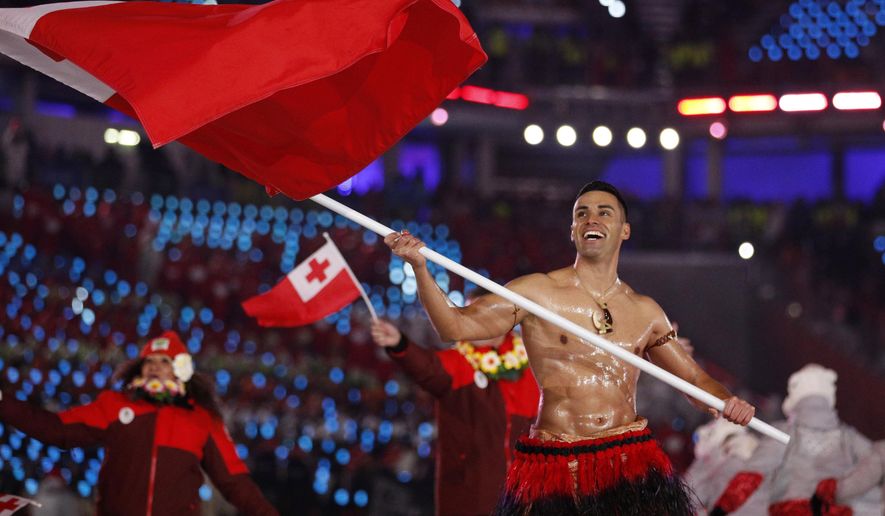 FILE - In this Feb. 9, 2018, file photo, Peta Taufatofua carries a flag of Tonga during the opening ceremony of the 2018 Winter Olympics in Pyeongchang, South Korea, Friday, Feb. 9, 2018. Taufatofua decided to leave his shirt on Tuesday, June 23, 2020 when he led a group of 23 fellow Olympians in a home workout video to help celebrate Olympic Day across 20 time zones. (AP Photo/Jae C. Hong, File)