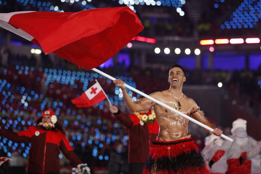 FILE - In this Feb. 9, 2018, file photo, Peta Taufatofua carries a flag of Tonga during the opening ceremony of the 2018 Winter Olympics in Pyeongchang, South Korea, Friday, Feb. 9, 2018. Taufatofua decided to leave his shirt on Tuesday, June 23, 2020 when he led a group of 23 fellow Olympians in a home workout video to help celebrate Olympic Day across 20 time zones. (AP Photo/Jae C. Hong, File)
