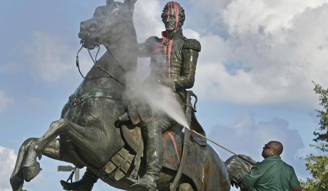 In this file photo, Ronnie English, a City of Jacksonville worker, pressure-washes the statue of Andrew Jackson after it was defaced with paint Monday, June 22, 2020, in downtown Jacksonville, Fla. (Will Dickey/The Florida Times-Union via AP)  **FILE**