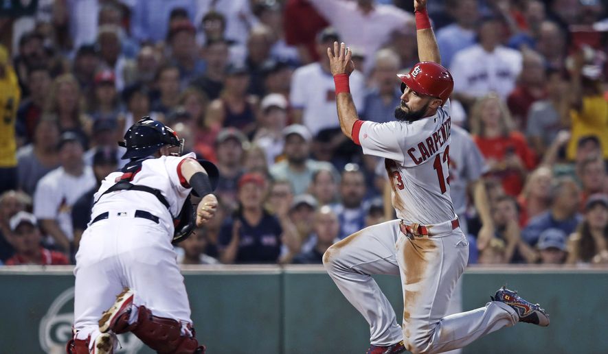 FILE - In this Aug. 16, 2017, file photo, St. Louis Cardinals' Matt Carpenter, right, tries unsuccessfully to avoid a tag by Boston Red Sox catcher Christian Vazquez during the second inning of a baseball game in Boston. The Cardinals and the Red Sox would have had one of their rare regular-season series this week. They have met in four different World Series. They would have played a three-game series at Fenway Park this week if not for the coronavirus pandemic. (AP Photo/Charles Krupa, File)