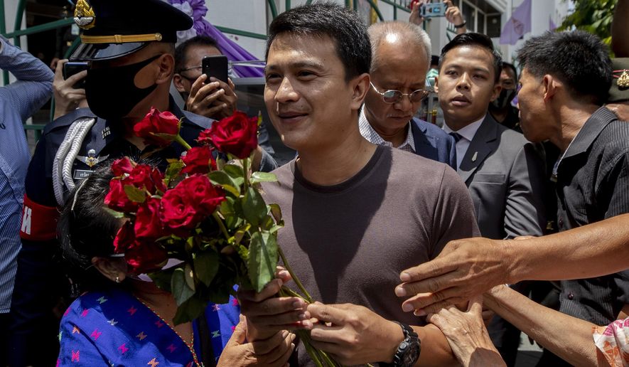 Sgt. Narongchai Intharakawi, center, receives roses from supporters as he arrives at military court in Bangkok, Thailand, Monday, June 22, 2020. The Thai sergeant who alleged corruption was rampant in his unit has been granted bail by a military court after his arrest for abandoning his post because he fled the army fearing for his safety. (AP Photo/Sakchai Lalit)