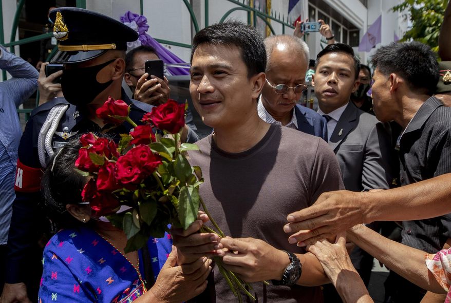 Sgt. Narongchai Intharakawi, center, receives roses from supporters as he arrives at military court in Bangkok, Thailand, Monday, June 22, 2020. The Thai sergeant who alleged corruption was rampant in his unit has been granted bail by a military court after his arrest for abandoning his post because he fled the army fearing for his safety. (AP Photo/Sakchai Lalit)