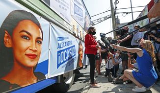 U.S. Rep. Alexandria Ocasio-Cortez, D, New York, center, meets a cluster of media beside a campaign truck plastered with her promotional material in Astoria, Queens, Tuesday, June 23, 2020, on primary election day in New York. (AP Photo/Kathy Willens) ** FILE **