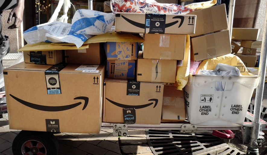 FILE - In this Oct. 10, 2018, file photo, Amazon Prime boxes are loaded on a cart for delivery in New York. Amazon said Tuesday, June 23, 2020, that its carbon footprint rose 15% last year, even as it launched initiatives to reduce its harm on the environment. (AP Photo/Mark Lennihan, File)