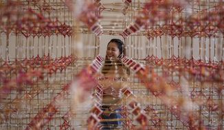 A woman looks through an art installation of Rattana Sudjarit at the Bangkok Art and Cultural Center in Bangkok, Thailand, Tuesday, June 23, 2020. Daily life in the capital is resuming to normal as the Thai government continues to ease restrictions related to running business and activities that were imposed weeks ago to combat the spread of COVID-19. (AP Photo/ Gemunu Amarasinghe)