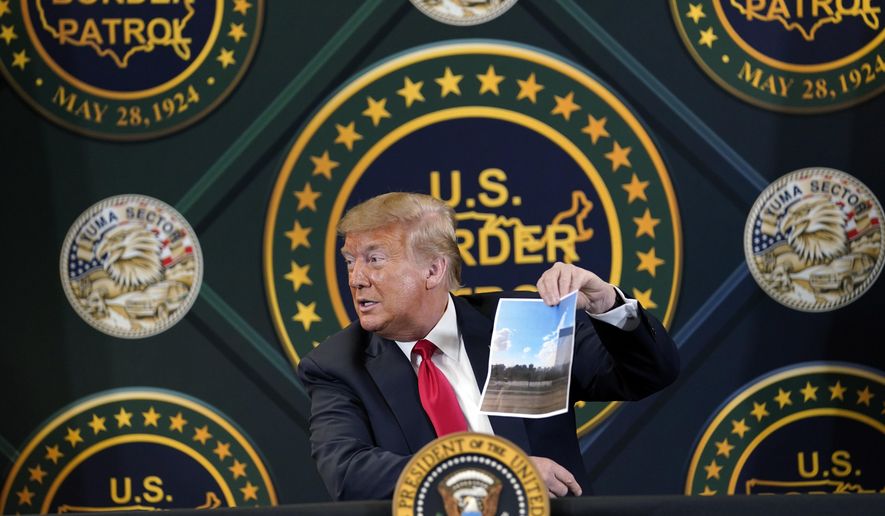 President Donald Trump holds an image of the U.S. border wall being built between the U.S. and Mexico as he participates in a border security briefing at United States Border Patrol Yuma Station, Tuesday, June 23, 2020, in Yuma, Ariz. (AP Photo/Evan Vucci)