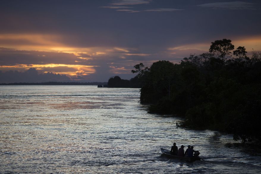 FILE - In this May 22, 2014 file photo, a small boat navigates on the Solimoes River near Manaus, Brazil. In the remote Amazon community of Betania, indigenous Tikuna tribe members suspect the new coronavirus arrived in May of 2020 after some returned from a two-hour boat trip down the Solimoes River to pick up their government benefit payments. (AP Photo/Felipe Dana, File)
