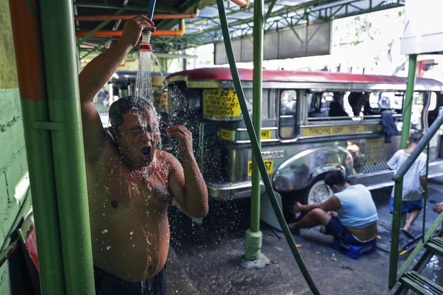 Jeepney driver Jude Recio takes a shower at the Tandang Sora terminal which have been home for them since a lockdown started three months ago, on Wednesday, June 17, 2020 in Quezon city, Philippines. About 35 jeepney drivers were forced to stay due to travel restrictions and have made jeepneys their home as the government banned public transport during the community quarantine to prevent the spread of the new coronavirus. Many of the jobless drivers have resorted to begging in the streets, displaying cardboard signs scrawled with pleas for money and food on their multi-colored jeepneys. (AP Photo/Aaron Favila)