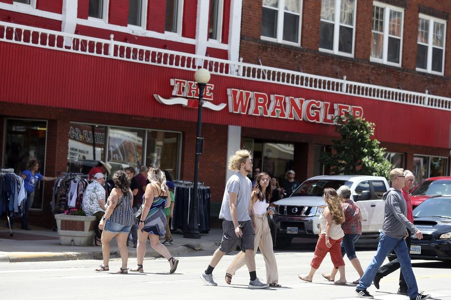 In this Friday, June 19, 2020, photo people walk outside during a "Summertime On The Streets" event that drew hundreds to downtown Cheyenne, Wyo., and raised concern that people not wearing masks could worsen a spike in coronavirus cases. (Michael Cummo/Wyoming Tribune Eagle via AP)