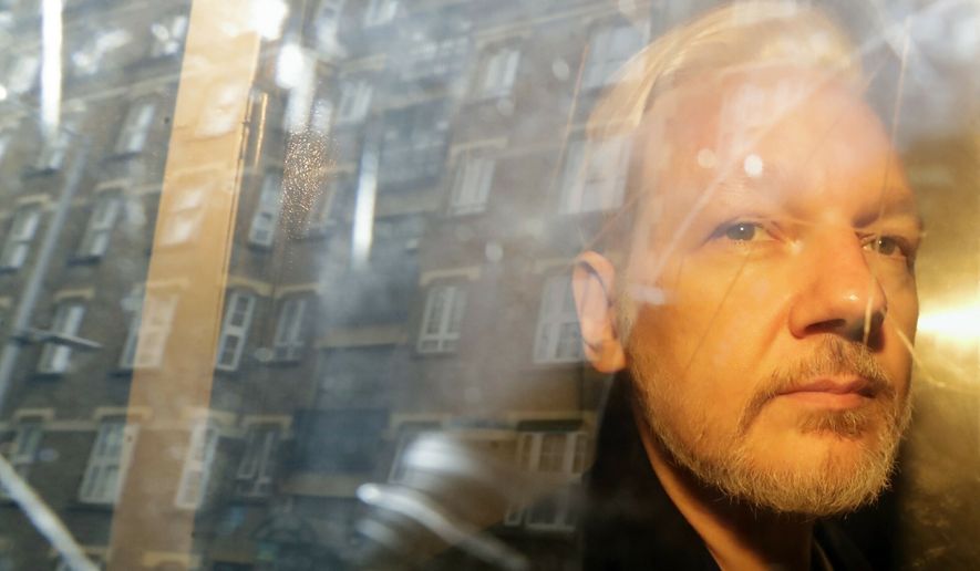 In this May 1, 2019, file photo, buildings are reflected in the window as WikiLeaks founder Julian Assange is taken from court in London. (AP Photo/Matt Dunham, File)