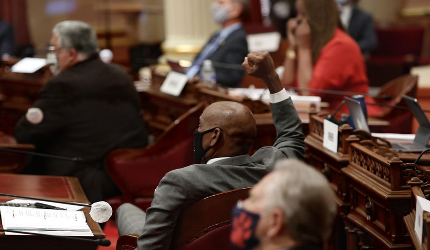 State Sen. Steve Bradford, D-Gardena, center, raises his fist in celebration as the Senate approves a measure to place a proposed Constitutional amendment on the November ballot to overturn its ban on affirmative action programs, at the Capitol, in Sacramento, Calif., Wednesday, June 24, 2020. California has banned it's public universities and government agencies from considering race in their admissions and hiring decisions since 1996. (AP Photo/Rich Pedroncelli)