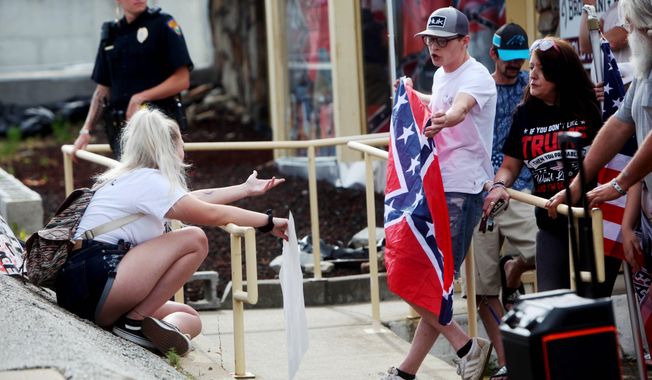 Black Lives Matter protesters face off with several counter-protesters during a demonstration in the parking lot by Dixie Outfitters Sunday, June 21, 2020 in Branson, Mo. Protesters have been gathering outside the strip mall store, which specializes in Confederate flags, clothing and other merchandise. The protests have drawn people from opposing sides of the debate — Black Lives Matter demonstrators, as well as those who support the store and the Confederate flag. (Sara Karnes/The Springfield News-Leader via AP)