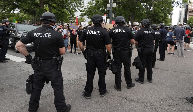 In this May 29, 2020, photo, Denver Police officers form a line of defense as they square off with participants in a protest over the death of George Floyd. (AP Photo/David Zalubowski) **FILE**