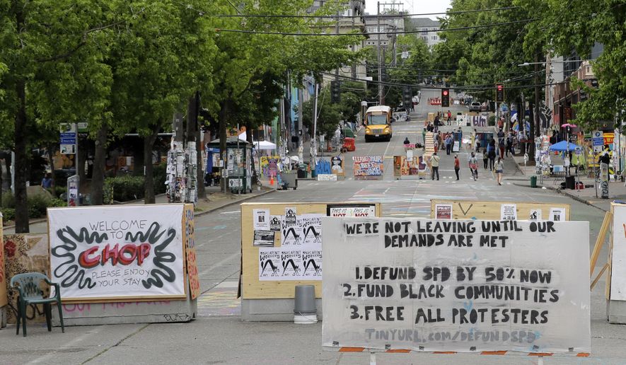 A sign on the street welcomes visitors and a list of demands is posted Wednesday, June 24, 2020, inside the CHOP (Capitol Hill Occupied Protest) zone in Seattle. The area has been occupied since a police station was largely abandoned after clashes with protesters, but Seattle Mayor Jenny Durkan said Monday that the city would move to wind down the protest zone following several nearby shootings and other incidents that have distracted from changes sought peaceful protesters opposing racial inequity and police brutality. (AP Photo/Ted S. Warren)