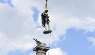 The statue of former U.S. vice president and slavery advocate John C. Calhoun hovers above its monument after contractors completed a 17-hour removal process on Wednesday, June 24, 2020, in Charleston, S.C. (AP Photo/Meg Kinnard)