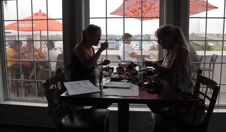 FILE- In this June 22, 2020, file photo two women eat lunch indoors at Portside Restaurant in Salisbury, Mass., after COVID-19 state guidelines allowed for indoor dining. A new poll from The Associated Press-NORC Center for Public Affairs Research shows Americans becoming less concerned about infection and less supportive of restrictions. But with experts warning that hospitals in some states in the South and West will soon be inundated, the poll finds many Americans have not embraced reopening even as state and local officials have. (AP Photo/Elise Amendola, File)