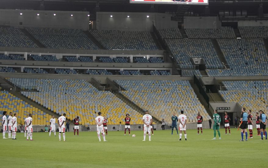 Players of Bangu, wearing white uniforms, and Flamengo pay a minute of silence for the victims of the coronavirus prior to a Rio de Janeiro soccer league match at the Maracana stadium in Rio de Janeiro, Brazi, Thursday, June 18, 2020. Rio de Janeiro's soccer league resumed after a three-month hiatus because of the coronavirus pandemic. The match is being played without spectators to curb the spread of COVID-19. (AP Photo/Leo Correa)