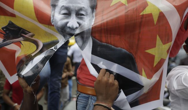 A Karni Sena supporter tears a banner featuring Chinese President Xi Jinping and shout slogans during a protest against China in Ahmedabad, India, Wednesday, June 24, 2020. Chinese and Indian military commanders have agreed to disengage their forces in a disputed area of the Himalayas following a clash that left at least 20 soldiers dead, both countries said Tuesday. The commanders reached the agreement Monday in their first meeting since the June 15 confrontation, the countries said. (AP Photo/Ajit Solanki)