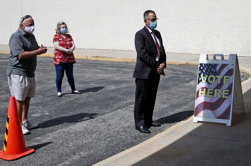 Oklahoma State Treasurer Randy McDaniel, right, practices social distancing with other voters as he waits to vote in early voting for Oklahoma's June 30th primary and special election, at the Oklahoma County Election Board, in Oklahoma City, Thursday, June 25, 2020. (AP Photo/Sue Ogrocki)
