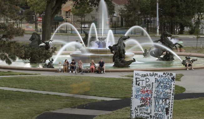 In this photo taken Tuesday, June 23, 2020, people gather at the J.C. Nichols fountain in Kansas City, Mo. The city&#x27;s board of parks and recreation is considering a proposal to remove the J.C. Nichols name from the fountain and a nearby street as they address racial concerns about the influential local developer. Nichols developed some of the area&#x27;s most desirable neighborhoods as well as the city&#x27;s County Club Plaza shopping district in the early 1900&#x27;s but excluded Blacks, Jews and other minorities using deed restrictions on his properties. (AP Photo/Charlie Riedel)